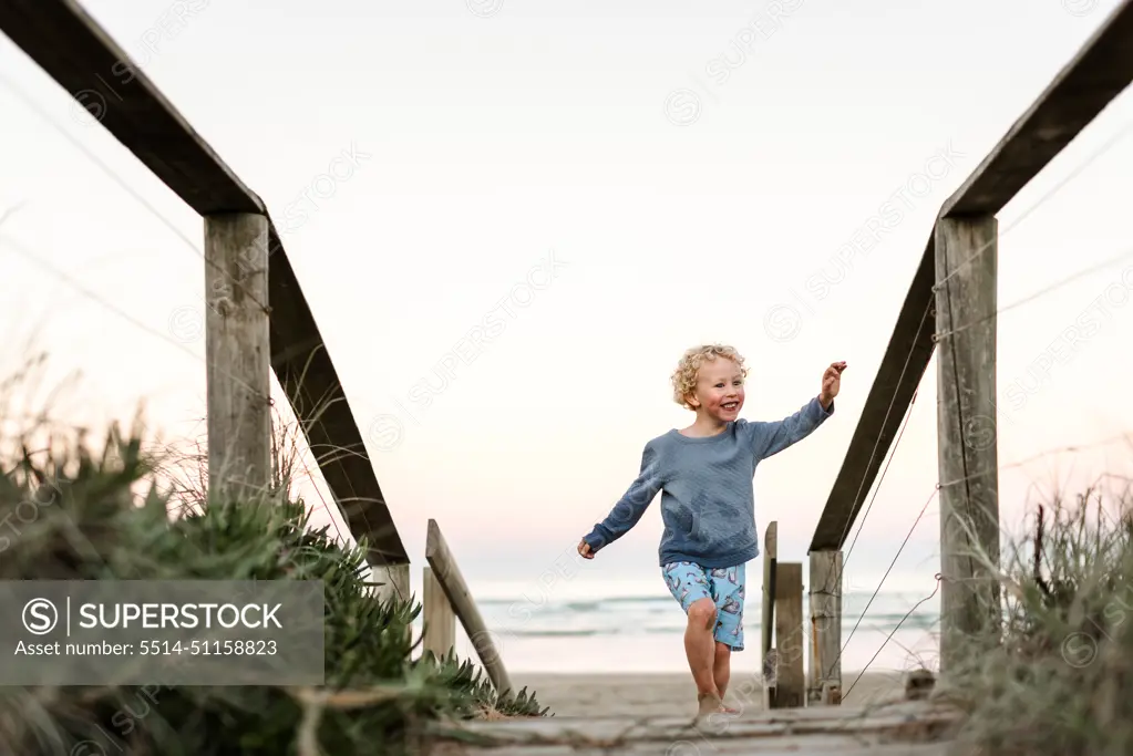 Happy boy on boardwalk at beach in New Zealand