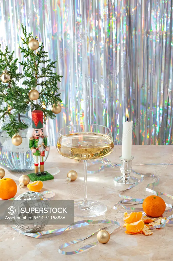 New Year's atmosphere, a glass of champagne, confetti, a lit candle