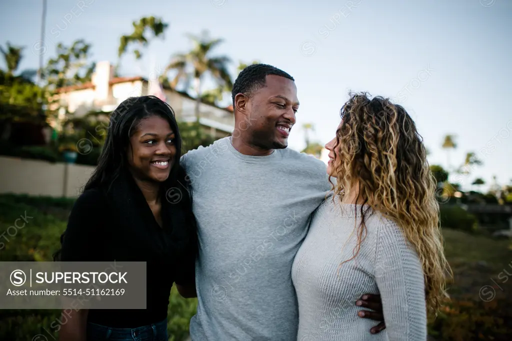 Blended family smiling at one another on beach at sunset