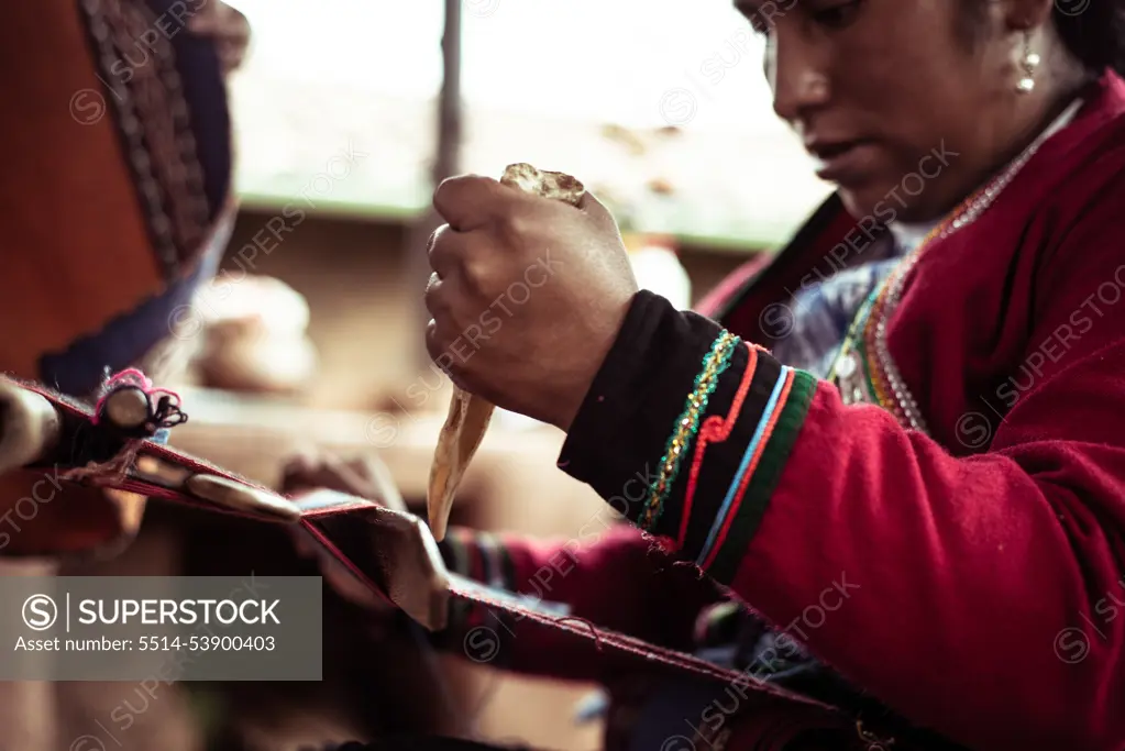 Local woman in traditional clothes weaves alpaca wool with bone