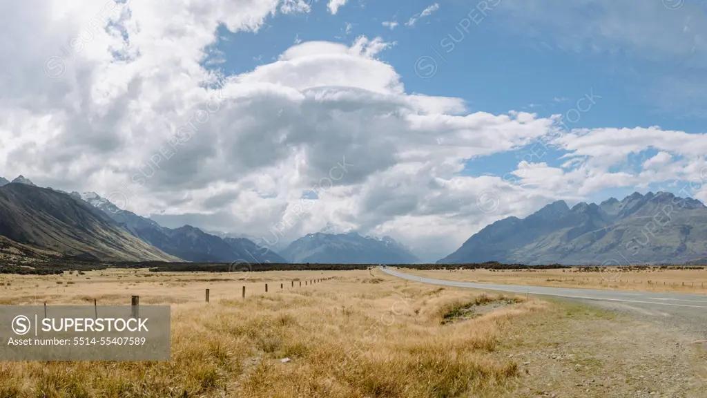 Rural road winds through grazing land and mountains in NZ countryside