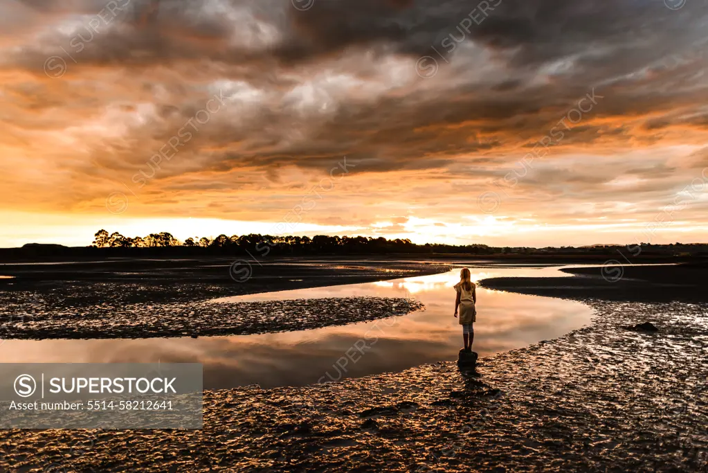 Girl watching beautiful sunset at an estuary in New Zealand