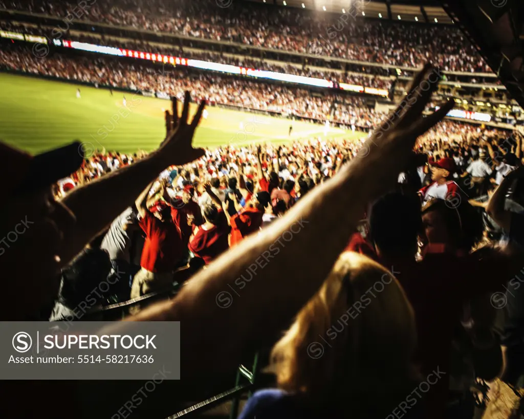 Baseball fans raising their arms.