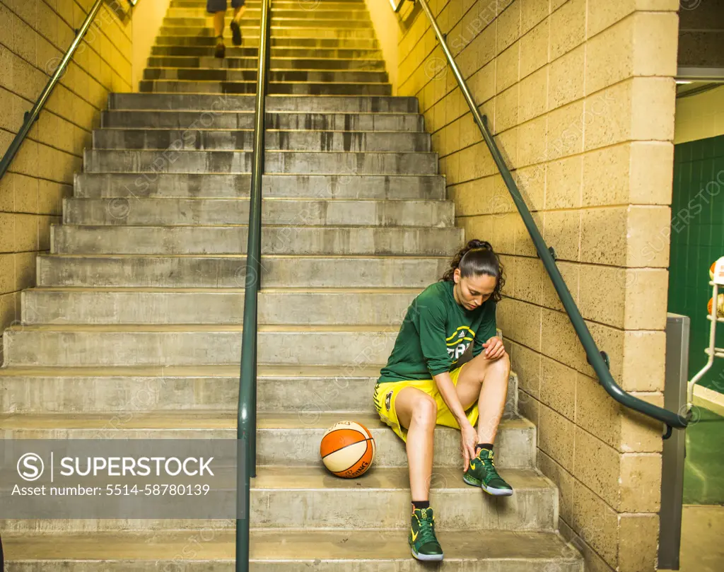 Female basketball player sitting on steps and preparing for game, Seattle, Washington, USA