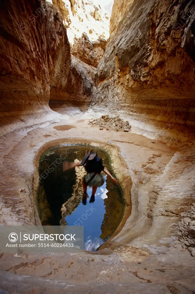 woman jumping into pool in desert canyon, Grand Canyon, Arizona