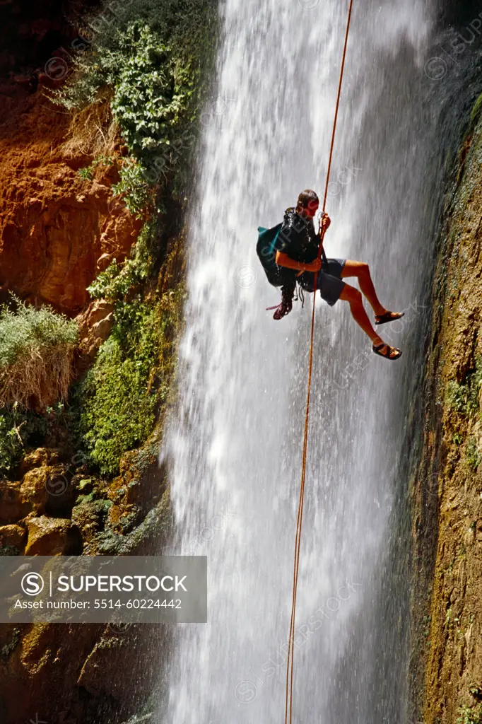 A man rappelling next to a waterfall, Grand Canyon, Arizona.