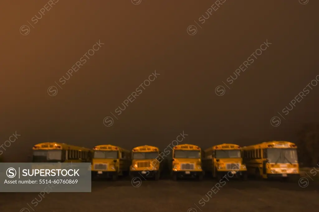 Buses sit in line beneath a brown colored, foggy sky. Auburn California.