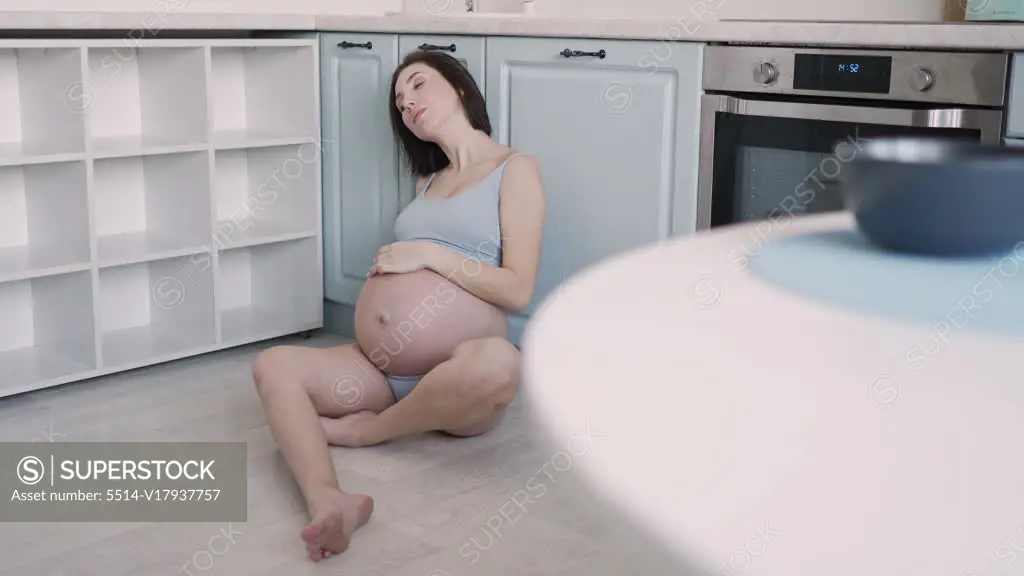 Foto de pregnant woman in underwear standing in her messy kitchen