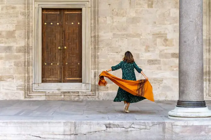 Woman in green dress and orange scarf exploring Istanbul on vacation