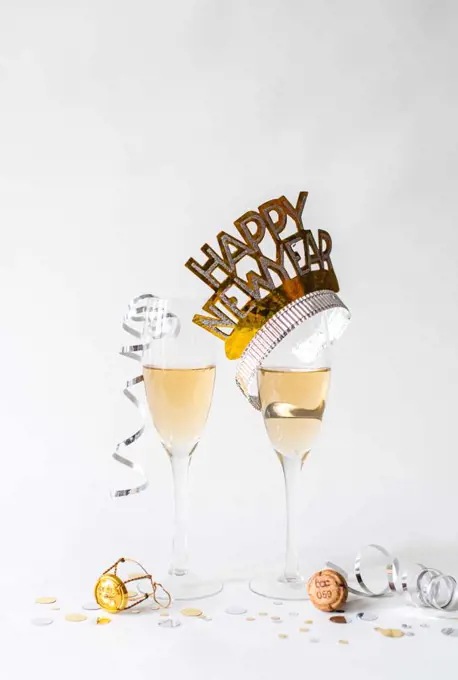 Glasses of champagne and Happy New Year hat on white background.