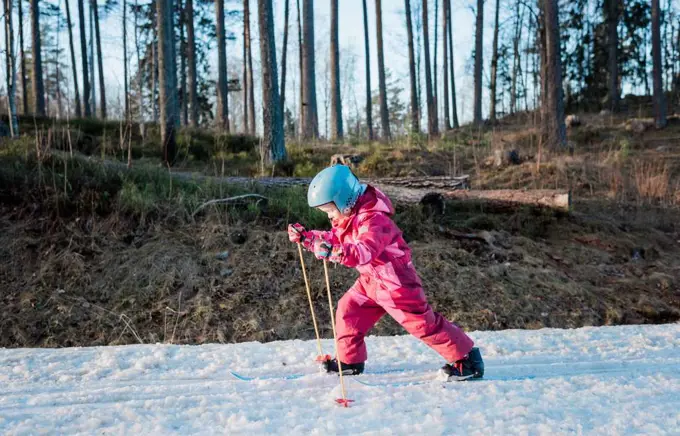 young girl cross country skiing in winter at sunset in Sweden