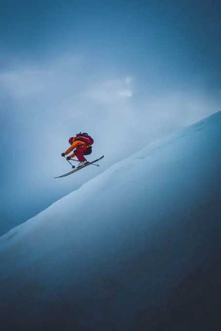 Skier going off ski jump with sky behind him