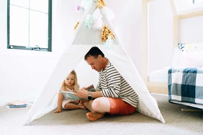 Closeup portrait of a dad and child reading together in a child's room