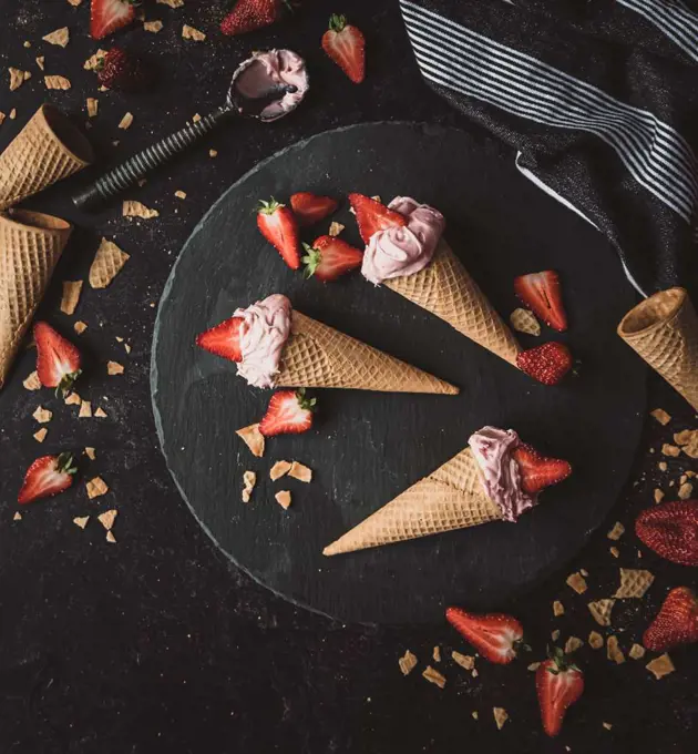 Top view of strawberry ice cream cones on a black background.