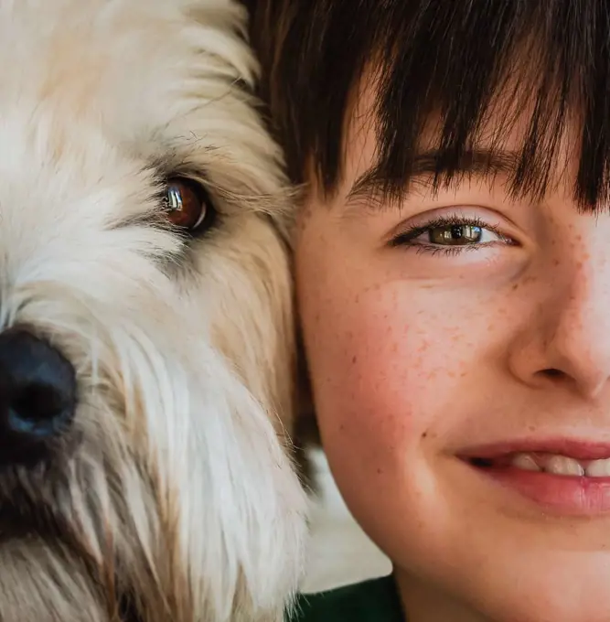 Close up of half of the faces of boy and his dog with heads together.