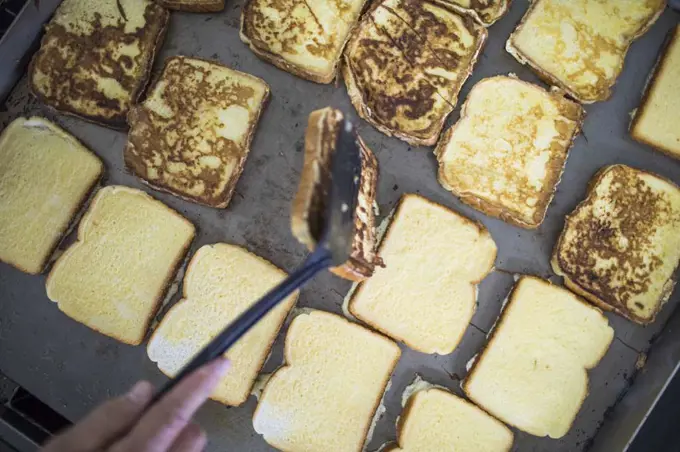 high angle view of chef flipping french toast on grill.