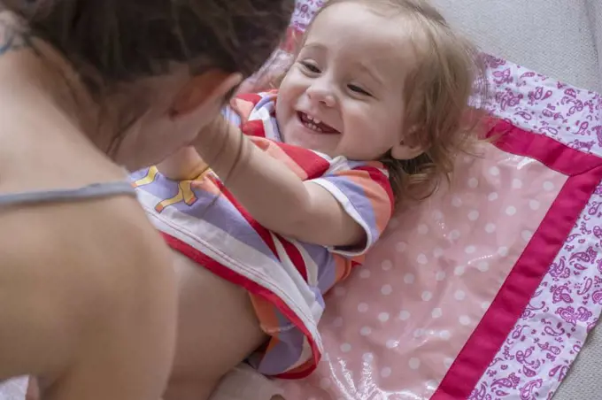 Mother changing diapers for her cute baby girl.