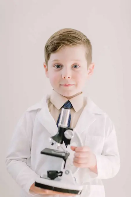 Young child holding a microscope smiling at camera