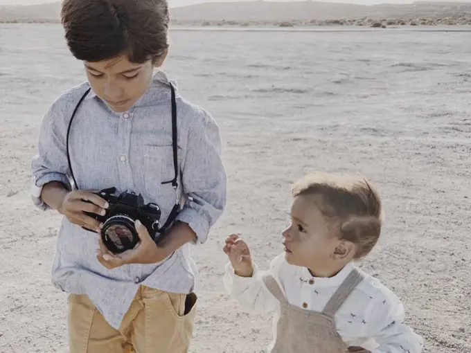 A kid holds a camera and a younger kid stands next to  me