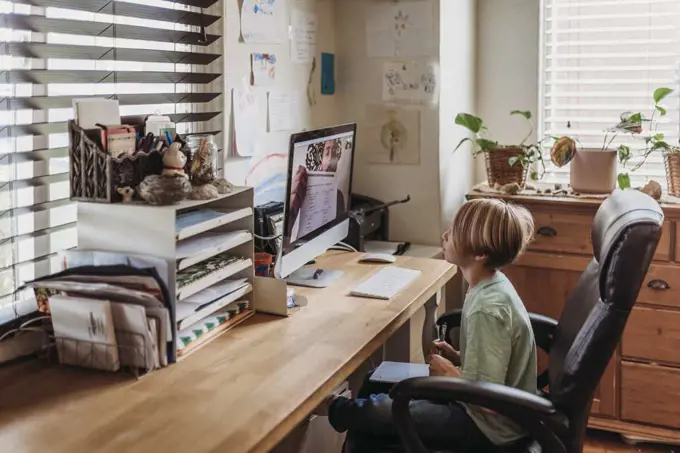 Side view of young student learning from teacher by remote education