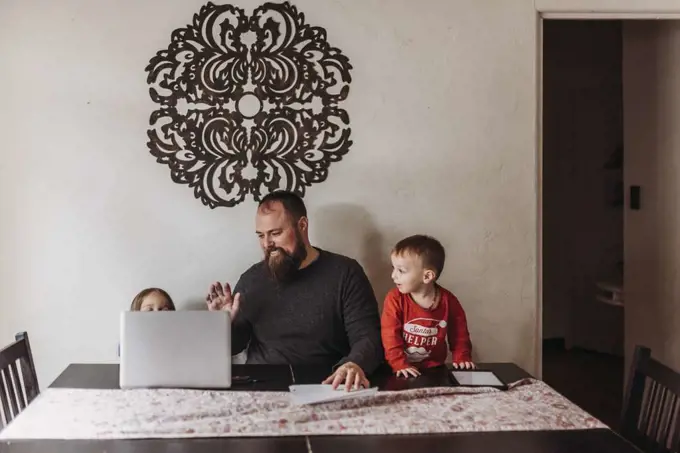 Young family video chatting and waving to family during isolation