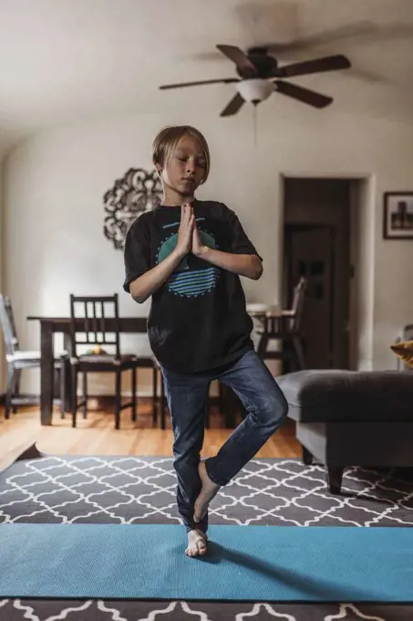 School-age boy doing yoga in living room during isolation