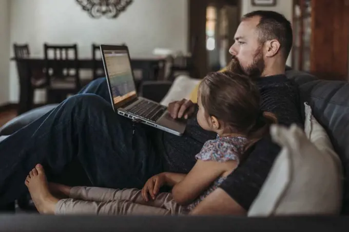 Father working from home with young daughter during isolation