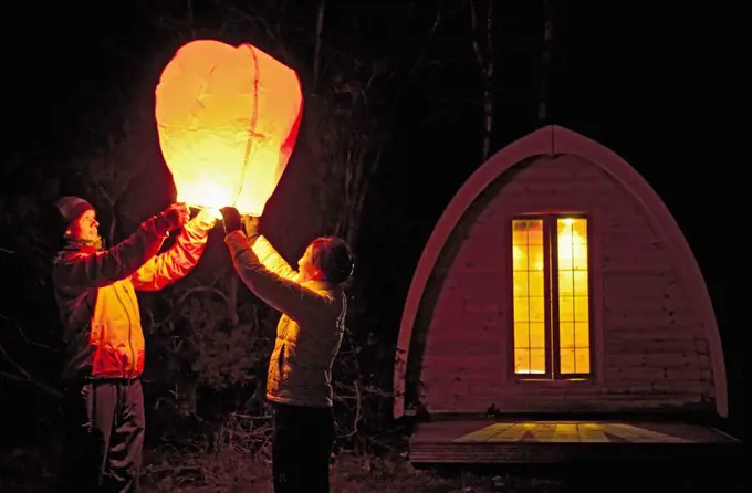 couple sending off Chinese lantern at campsite