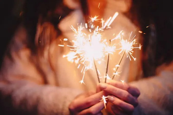 Female hands holding sparklers during Christmas in city