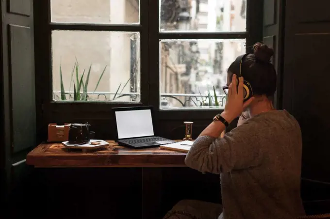 Young woman studies in a retro pub while she is listening music