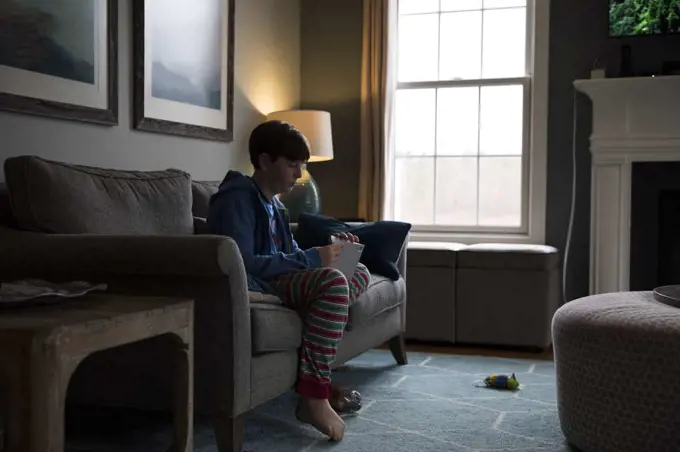 Side Silhouette of Teen Boy Sitting on Couch Opening A Letter