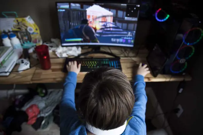 High View of Teen Boy Playing on Gaming Computer at Messy Desk