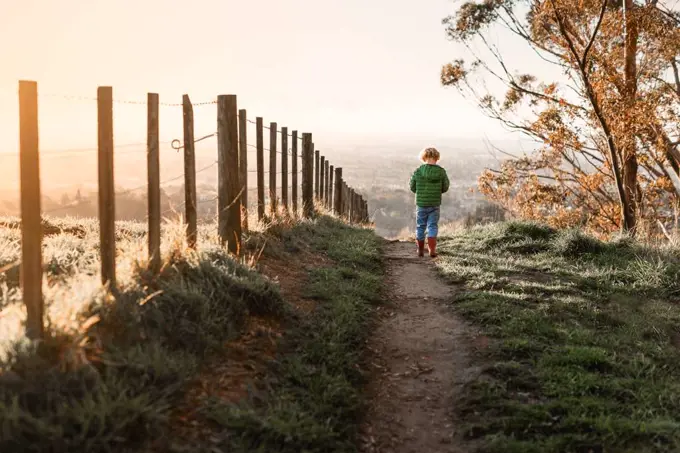 Child walking on path near fence at dusk in New Zealand