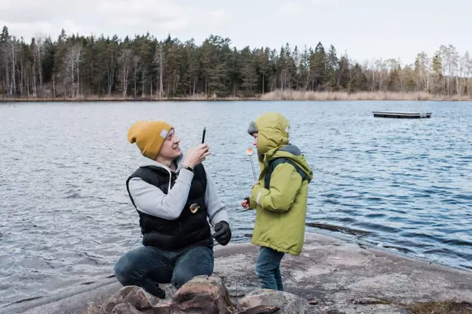 father taking pictures of his son whilst eating marshmallows