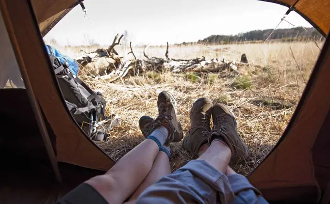 couple lying inside a tent with their feet outside