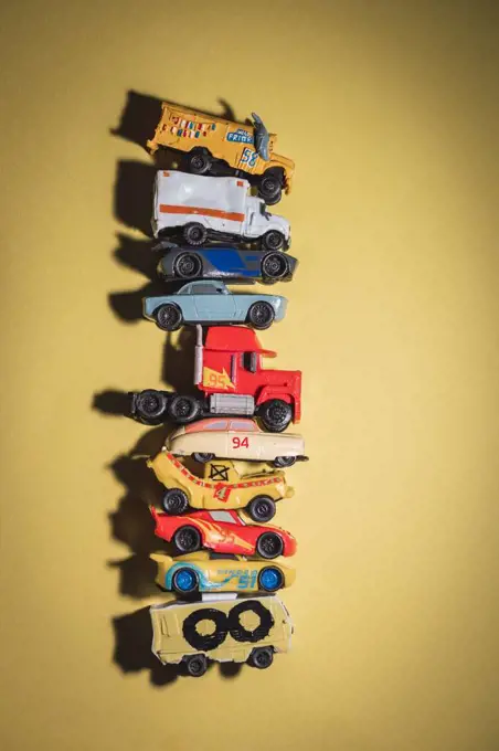 Toy cars stacked on top of each other on yellow background.