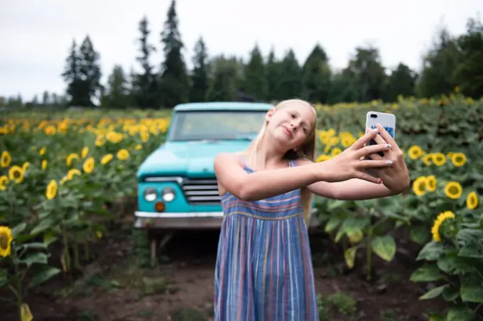 Young Girl Taking Selfie With Mobile Phone Standing on Sunflower Farm