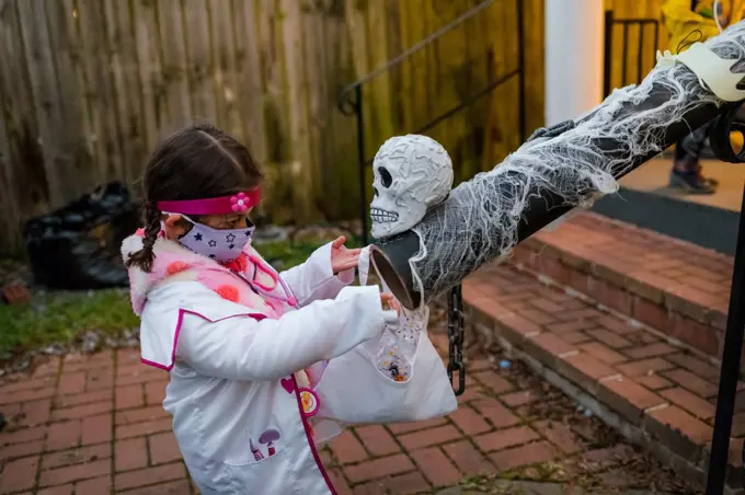 girl in doctor costume socially distant trick or treating candy chute