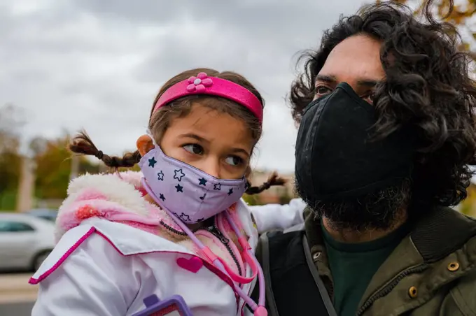 father and daughter with protective face masks and halloween costume