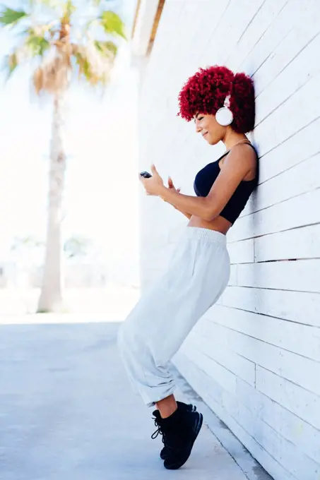 Woman with red afro hair listening music with headphones.