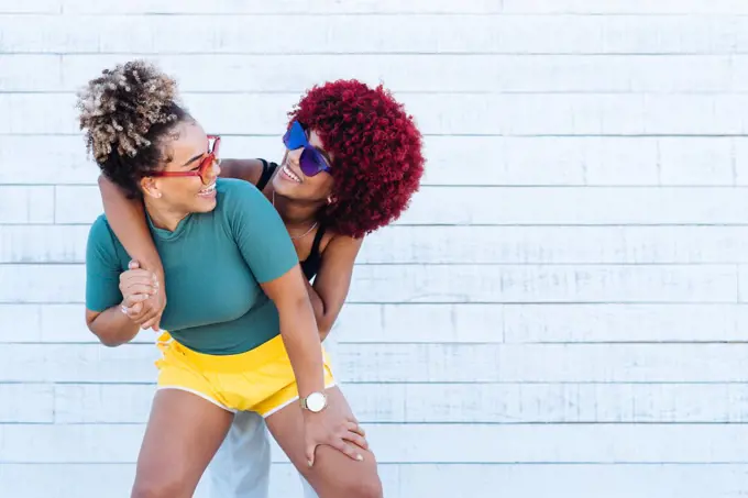 Two attractive latin girls with afro hair hugging each other amicably.