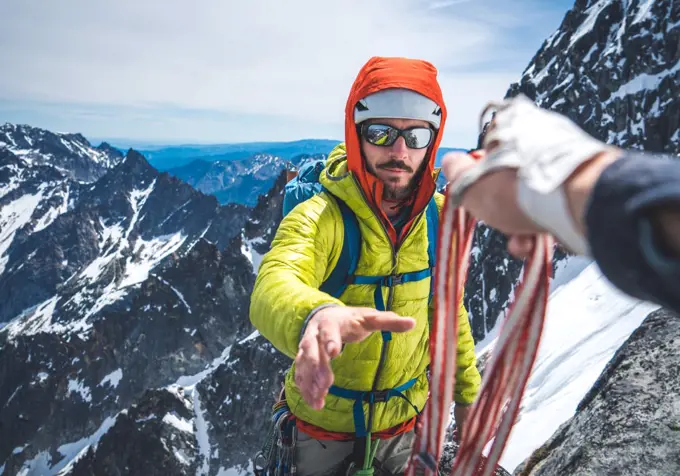 Man being handed gear during snowy alpine rock climb