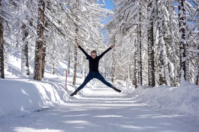 Happy young women jumping on the snow road