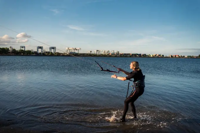 A woman in a wetsuit rigs up her kite before kiteboarding