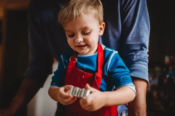 Adorable boy baking Christmas cookies with face full of flour