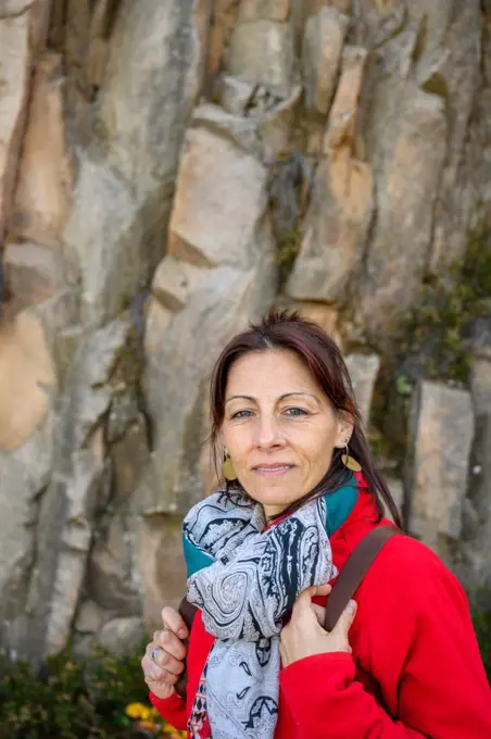 Laughing hiker woman with scarf and backpack, against stone formation