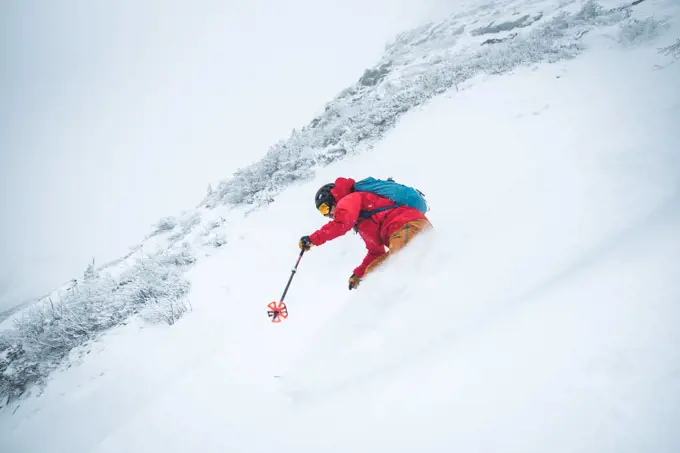 Man skiing in deep snow in the alpine during a snowstorm in Maine