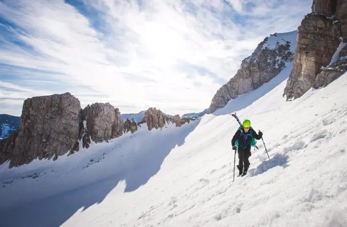 Man walking up steep snow section in California backcountry with skis