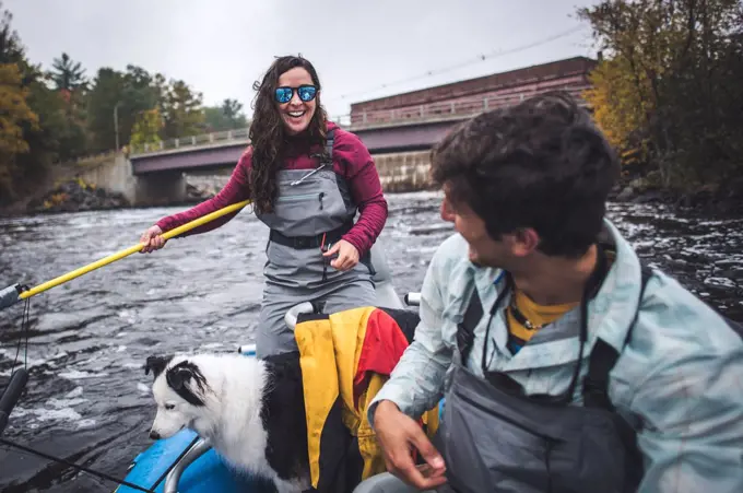 Woman smiling at man while fishing in boat below a dam on a river