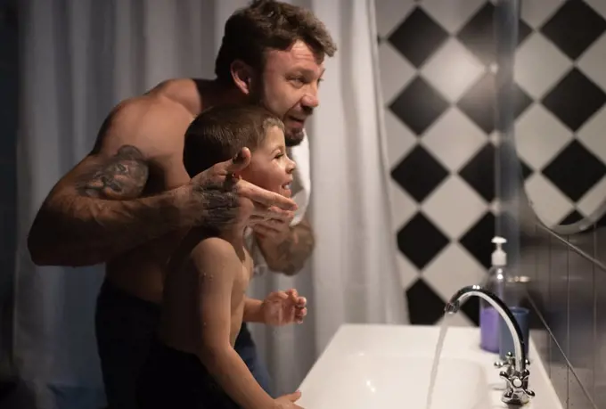 Father and son looking at mirror after shaving